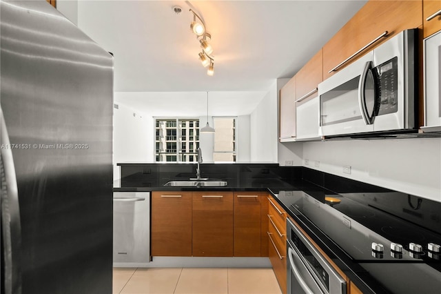 kitchen featuring sink, decorative light fixtures, light tile patterned floors, appliances with stainless steel finishes, and dark stone counters