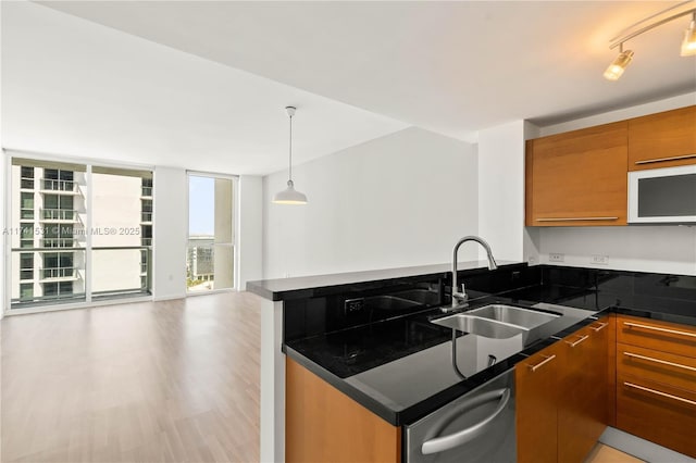 kitchen featuring rail lighting, sink, light wood-type flooring, pendant lighting, and a wall of windows