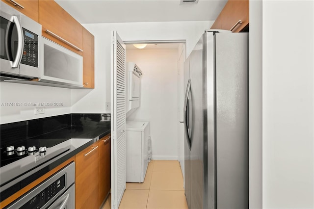 kitchen featuring stainless steel appliances, stacked washer / drying machine, and light tile patterned floors