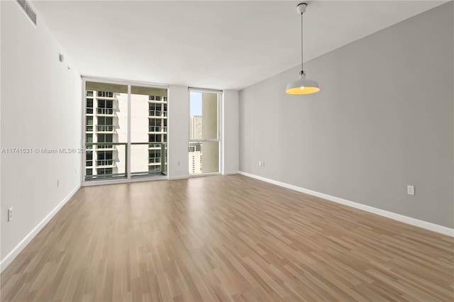 unfurnished room with hardwood / wood-style floors and floor to ceiling windows