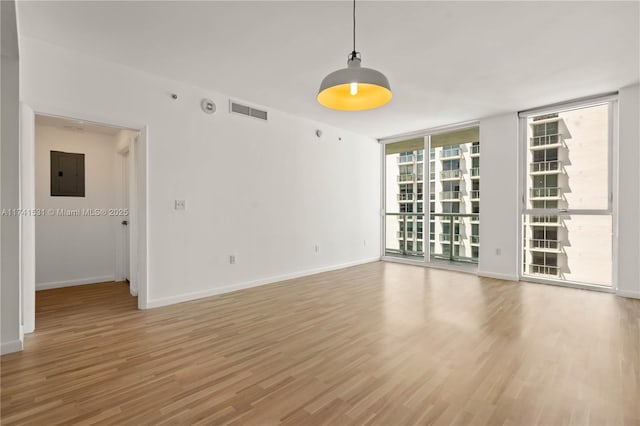 unfurnished room with hardwood / wood-style floors, electric panel, and a wall of windows