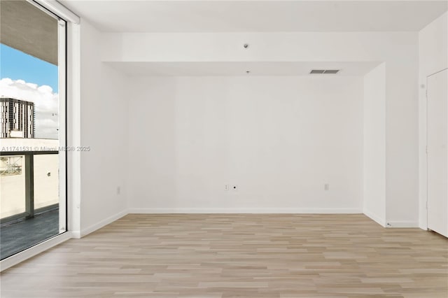 unfurnished room with floor to ceiling windows and light hardwood / wood-style floors