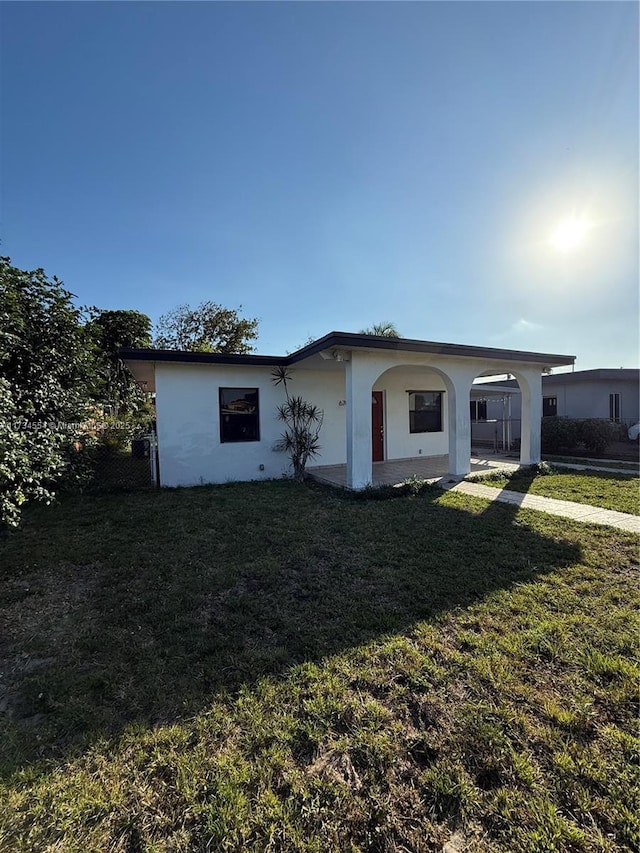 view of front of home with a carport and a front lawn