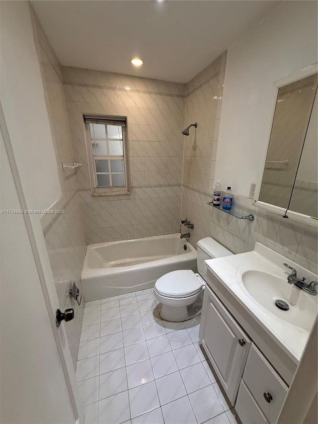 full bathroom with tiled shower / bath, tile walls, tile patterned flooring, vanity, and toilet