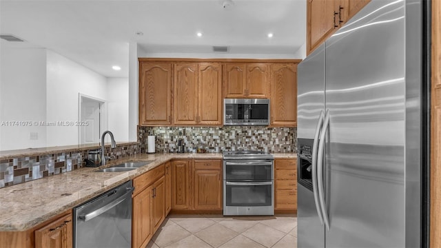 kitchen featuring light tile patterned flooring, sink, light stone counters, tasteful backsplash, and stainless steel appliances