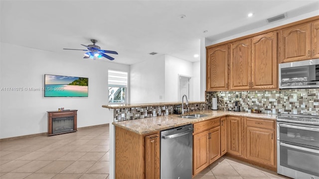 kitchen featuring light stone counters, sink, backsplash, and appliances with stainless steel finishes