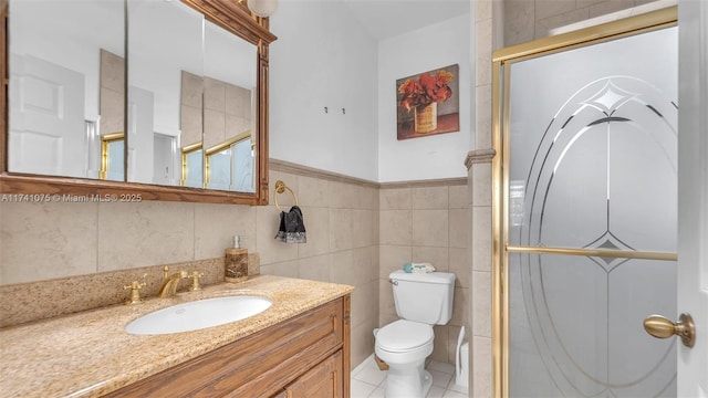 bathroom with a shower, tile walls, vanity, toilet, and tile patterned floors