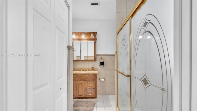 bathroom featuring vanity, tile walls, tile patterned floors, and walk in shower