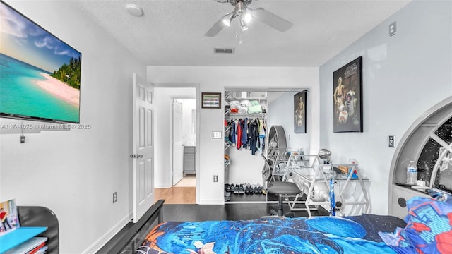 bedroom featuring ceiling fan, wood-type flooring, a closet, and a textured ceiling