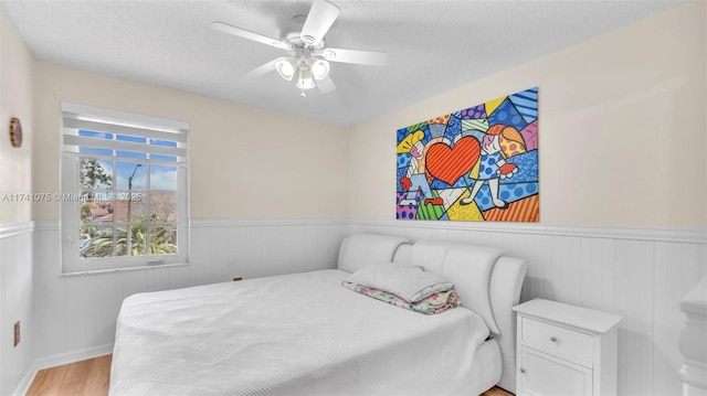 bedroom featuring ceiling fan, a textured ceiling, and light hardwood / wood-style flooring