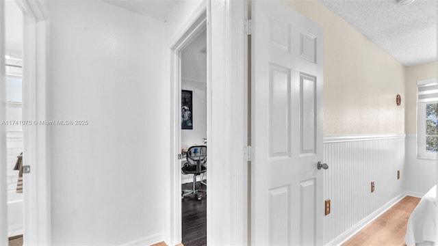 hallway featuring light hardwood / wood-style flooring and a textured ceiling