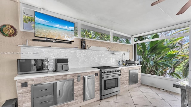 kitchen featuring tasteful backsplash, light tile patterned flooring, sink, and high end stove