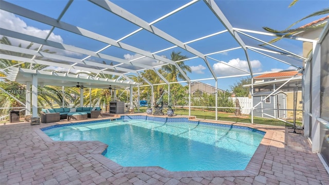 view of pool with a patio, outdoor lounge area, a lanai, ceiling fan, and a shed