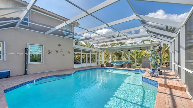 view of pool featuring an outdoor living space, ceiling fan, glass enclosure, and a patio area