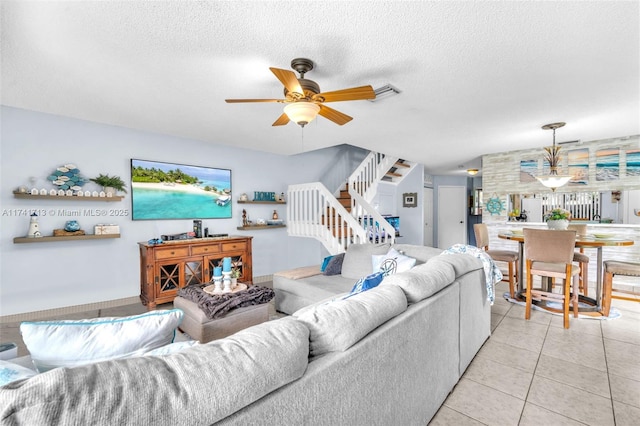 tiled living room with ceiling fan and a textured ceiling