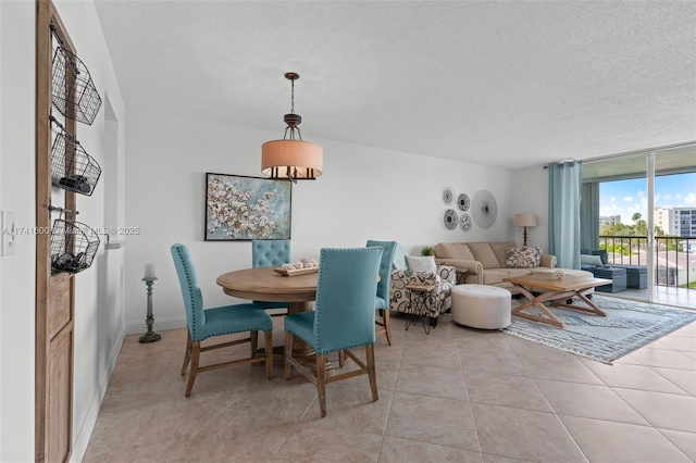 tiled dining space featuring a textured ceiling and a wall of windows