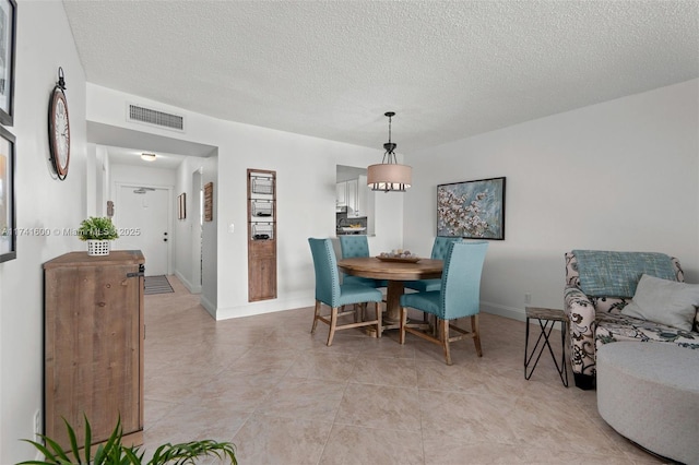 tiled dining space with a textured ceiling