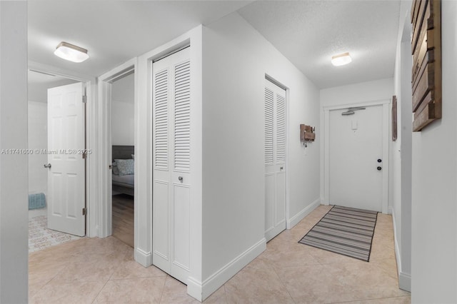 hallway featuring light tile patterned floors and a textured ceiling