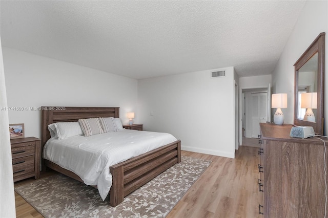 bedroom with light hardwood / wood-style flooring and a textured ceiling