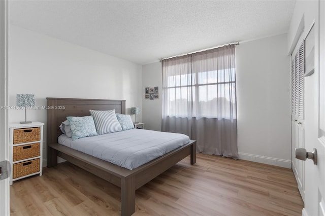 bedroom with a textured ceiling, light hardwood / wood-style floors, and a closet