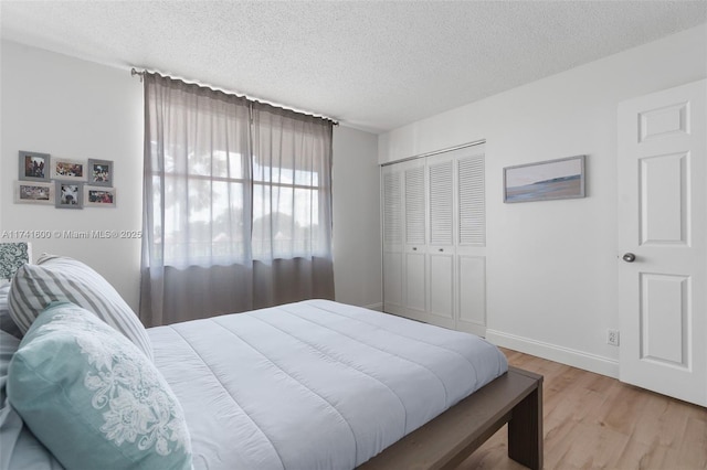 bedroom with light hardwood / wood-style floors, a closet, and a textured ceiling