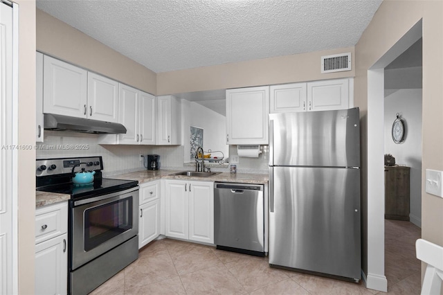 kitchen with sink, white cabinetry, light stone counters, light tile patterned floors, and appliances with stainless steel finishes