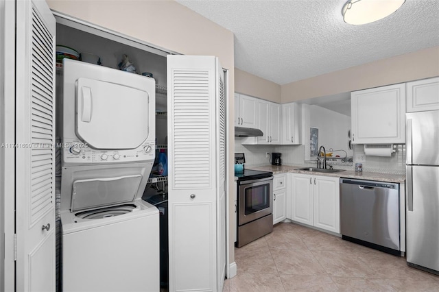 kitchen with white cabinetry, sink, stacked washer and clothes dryer, stainless steel appliances, and a textured ceiling