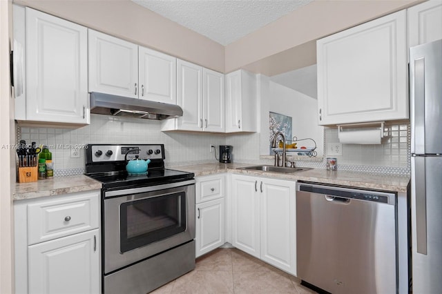 kitchen with sink, light tile patterned floors, appliances with stainless steel finishes, white cabinetry, and a textured ceiling