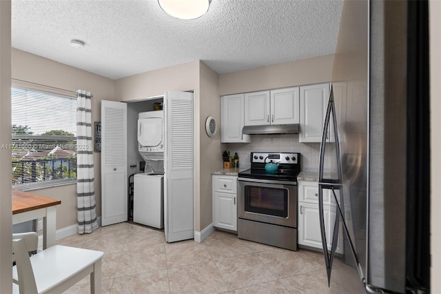 kitchen with tasteful backsplash, appliances with stainless steel finishes, stacked washing maching and dryer, and white cabinets