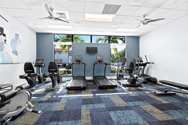 workout area featuring dark carpet, a wall of windows, ceiling fan, and a paneled ceiling