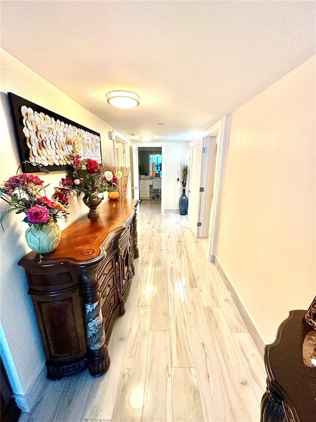 hallway with light hardwood / wood-style flooring and a textured ceiling