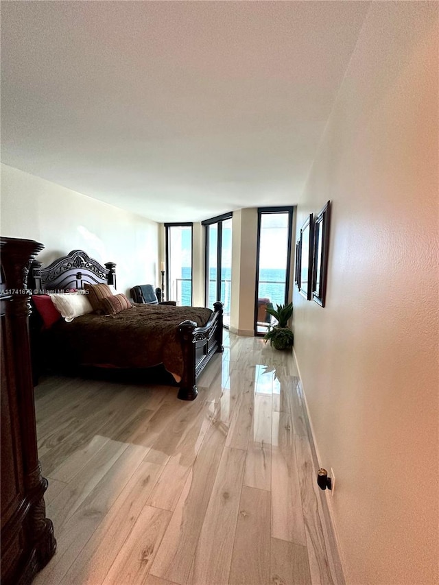 bedroom with a wall of windows and light hardwood / wood-style floors