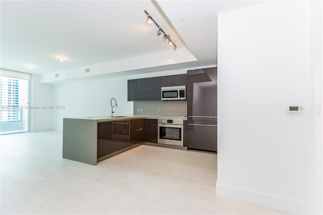 kitchen featuring stainless steel appliances, rail lighting, a raised ceiling, and sink