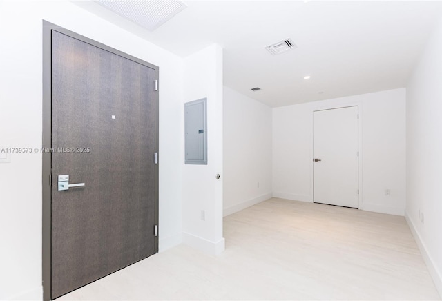 corridor with electric panel and light hardwood / wood-style floors