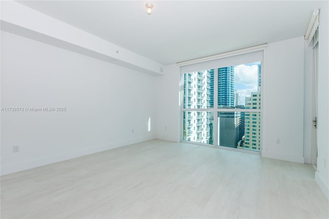 empty room featuring floor to ceiling windows and light hardwood / wood-style flooring