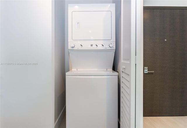 laundry room featuring stacked washer and dryer and light wood-type flooring