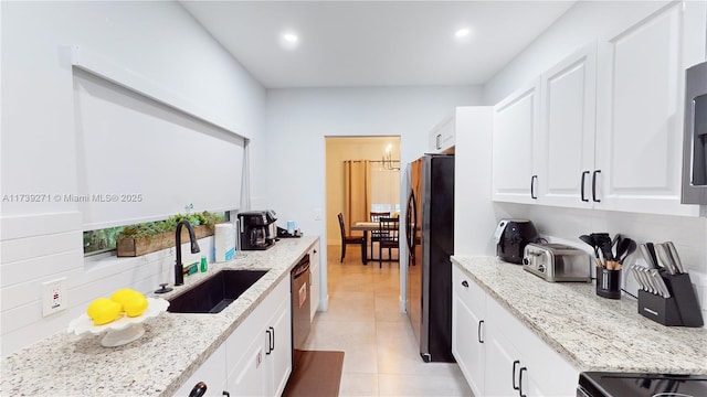 kitchen featuring sink, light stone counters, stainless steel refrigerator, range with electric cooktop, and white cabinets