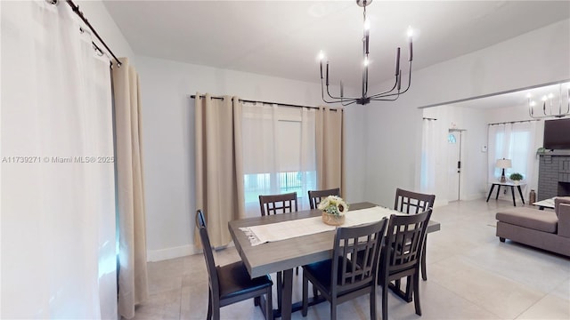 tiled dining room with a fireplace and a chandelier