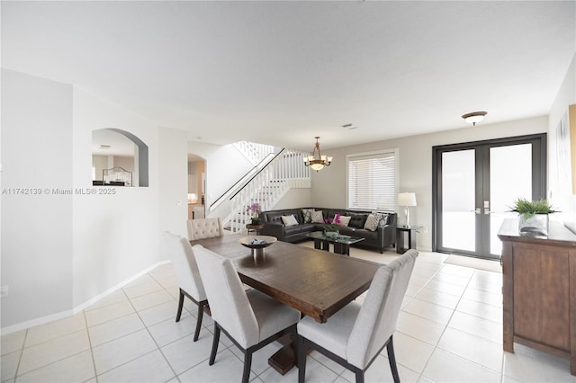 dining space featuring light tile patterned flooring, an inviting chandelier, and french doors