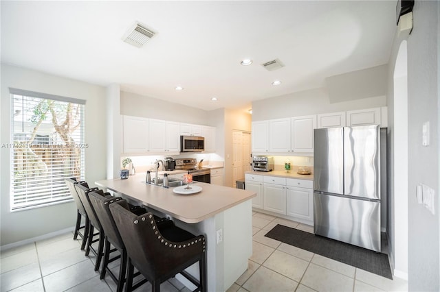 kitchen featuring a breakfast bar, kitchen peninsula, white cabinets, and appliances with stainless steel finishes