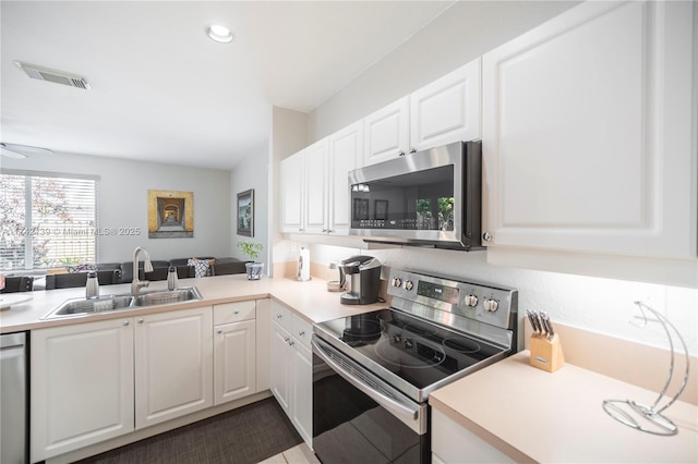 kitchen with sink, ceiling fan, stainless steel appliances, white cabinets, and kitchen peninsula