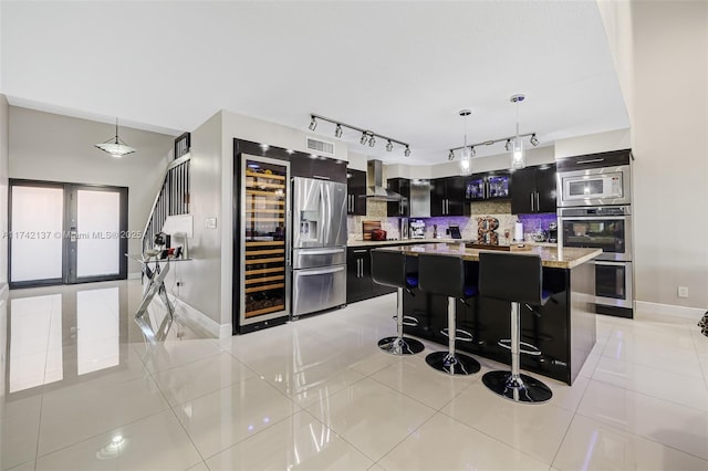 kitchen featuring a kitchen breakfast bar, hanging light fixtures, a center island, light stone counters, and wall chimney exhaust hood