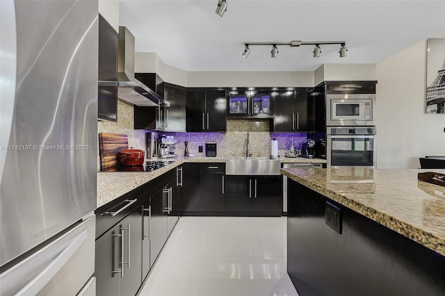 kitchen featuring sink, wall chimney range hood, light tile patterned floors, stainless steel appliances, and decorative backsplash