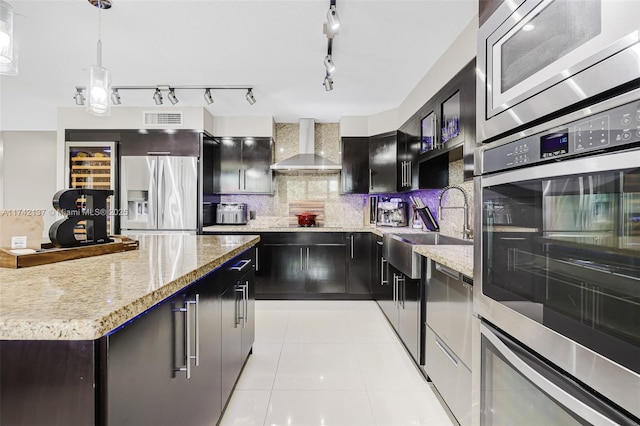 kitchen with appliances with stainless steel finishes, pendant lighting, sink, backsplash, and wall chimney exhaust hood