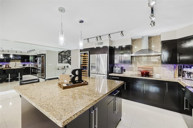 kitchen with a kitchen island, hanging light fixtures, black electric stovetop, stainless steel fridge with ice dispenser, and wall chimney exhaust hood