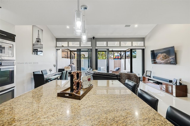 kitchen featuring light stone counters, stainless steel appliances, and decorative light fixtures