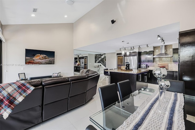 tiled living room featuring rail lighting and a towering ceiling