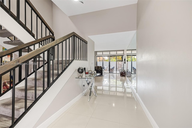 stairs with a towering ceiling and tile patterned floors