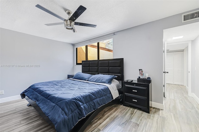 bedroom with hardwood / wood-style floors, a textured ceiling, and ceiling fan