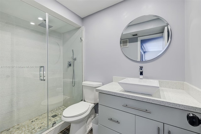 bathroom with vanity, toilet, and a shower with door